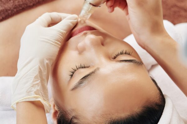 Vacuum skin cleaning Hands of beautician with electric vacuum tool cleaning face skin of young Asian woman