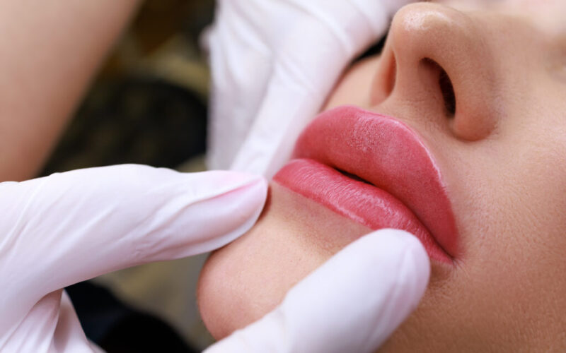 close-up of a permanent make-up master holding the lips of a model showing the completed work of permanent make-up of the lips